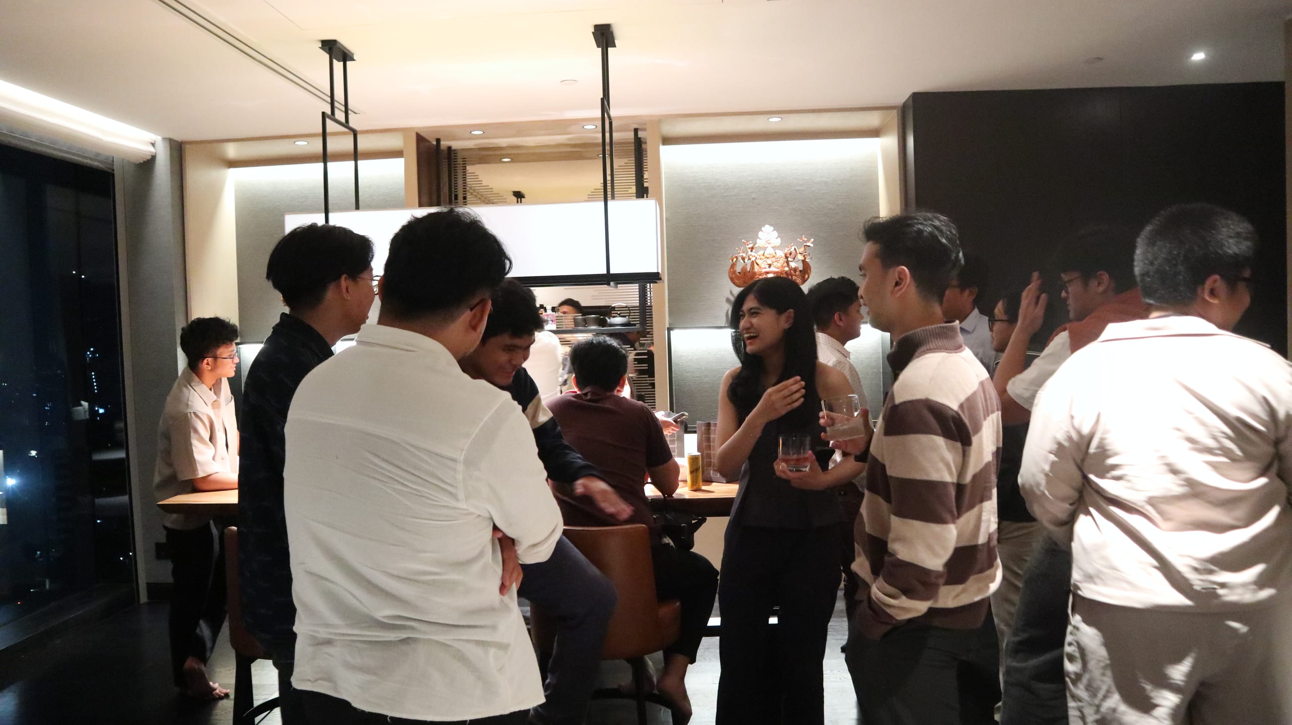 Guests standing and chatting over drinks at the Jakarta mixer