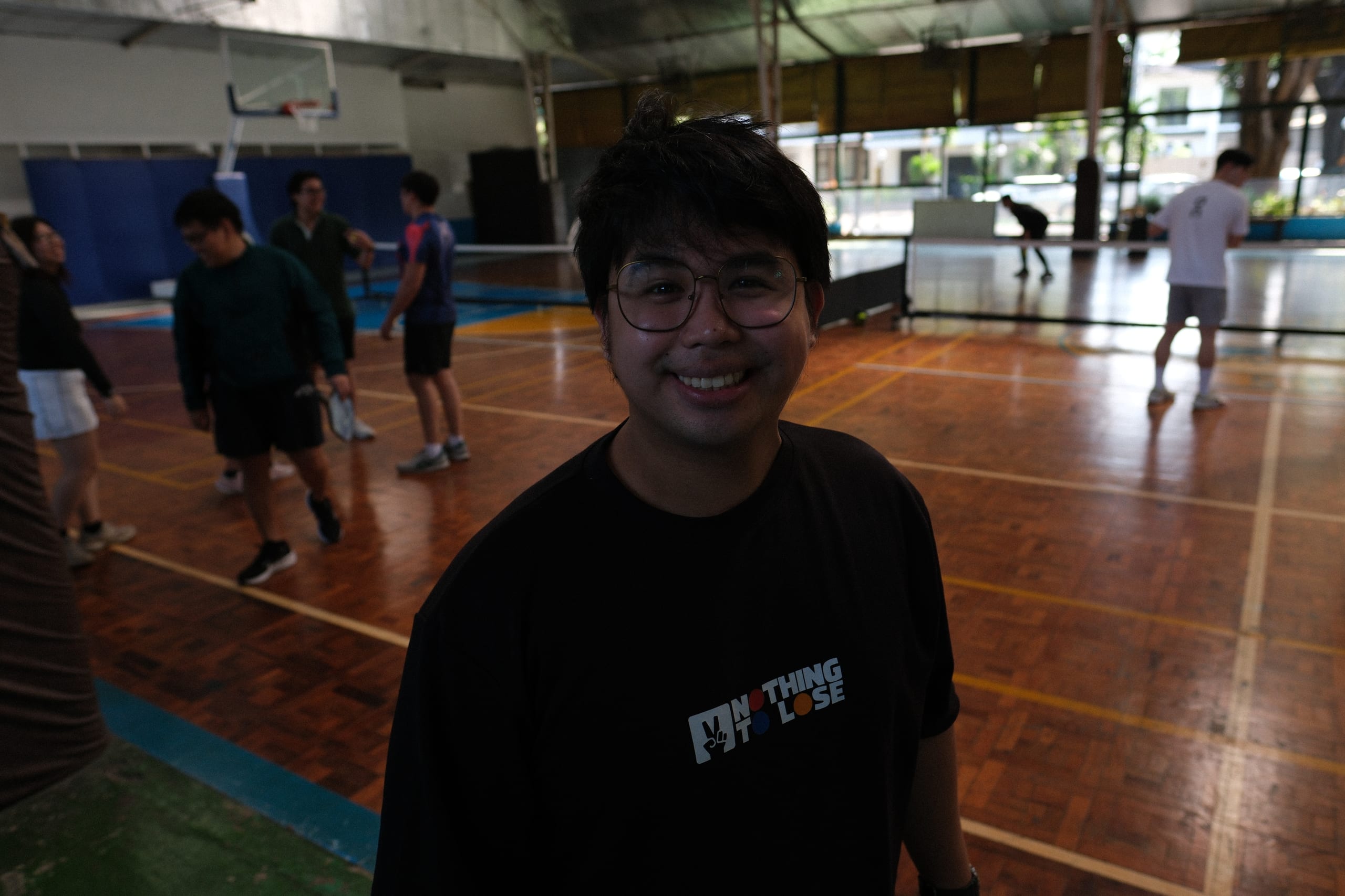 A smiling participant standing beside the pickleball court