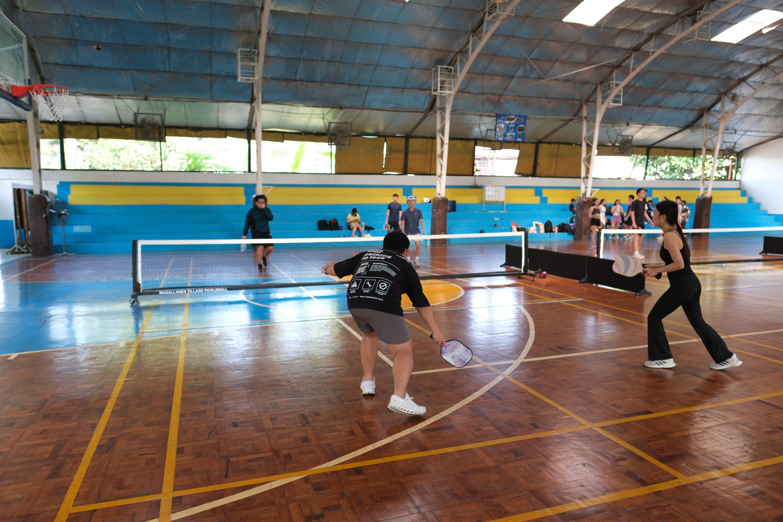 A pickleball player reaching low to return the ball