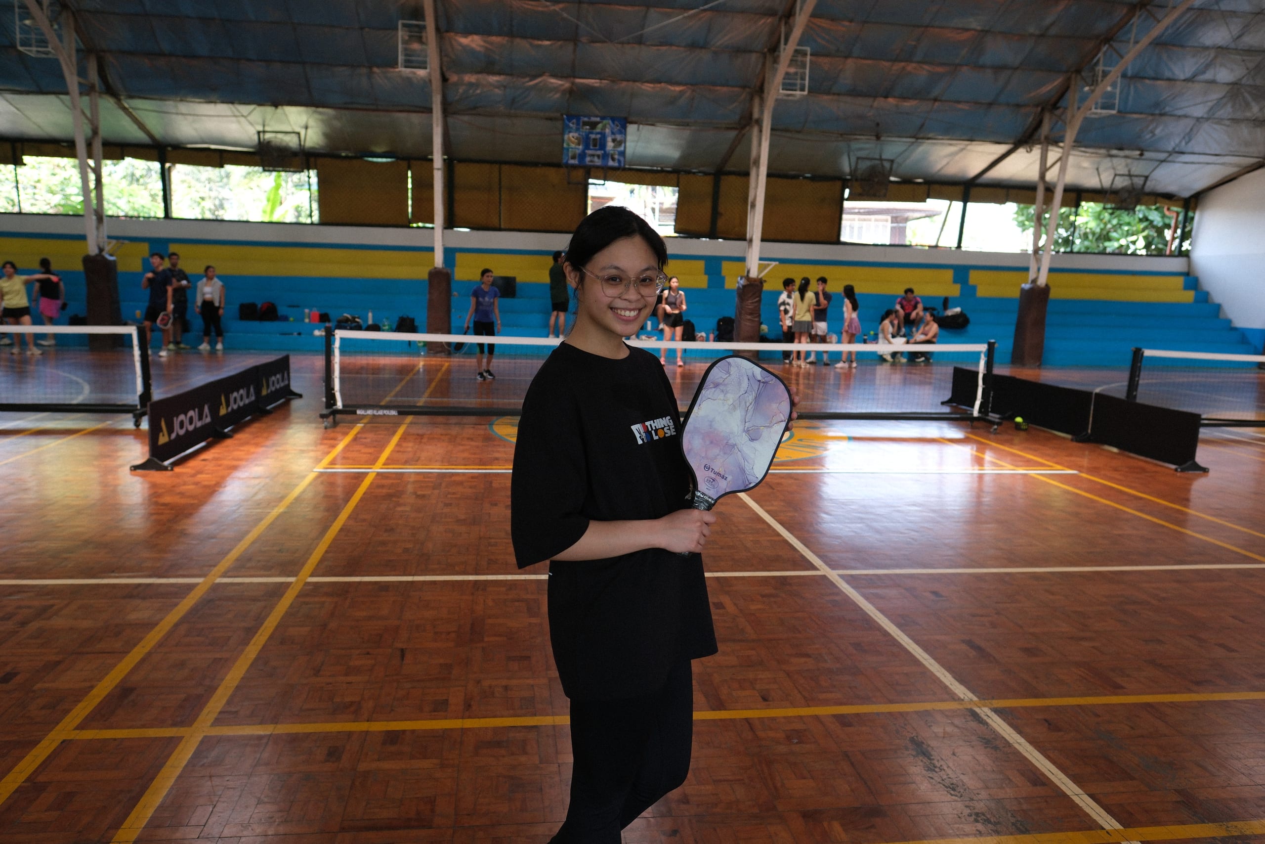 A smiling participant holding a pickleball paddle