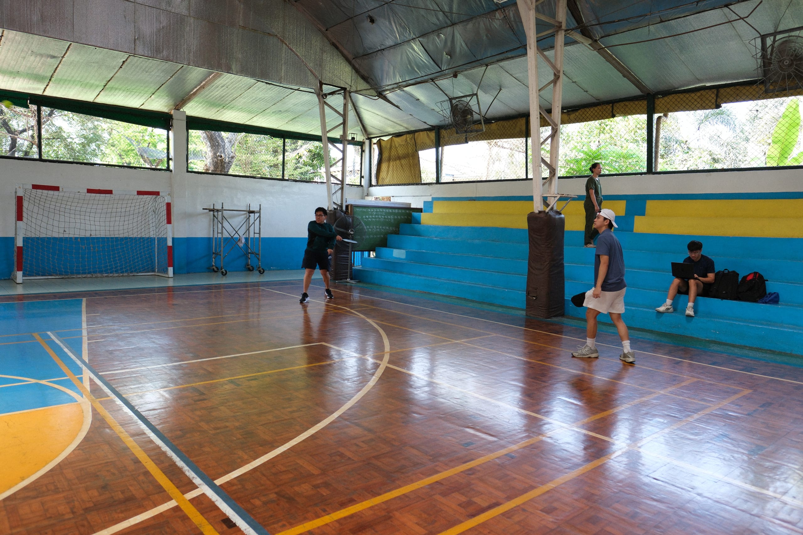 A pickleball player serving from the back of the court